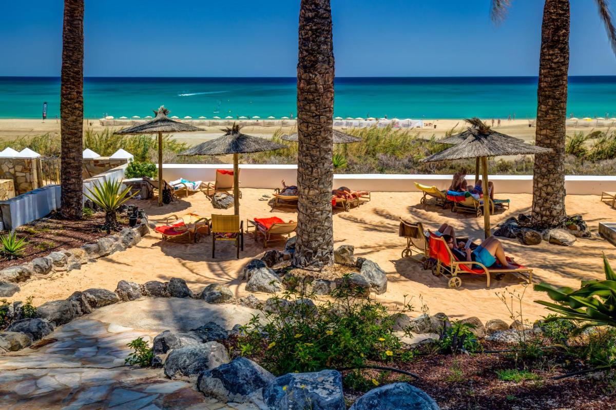 una playa con gente sentada en sillas y sombrillas en SBH Costa Calma Palace Thalasso & Spa, en Costa Calma