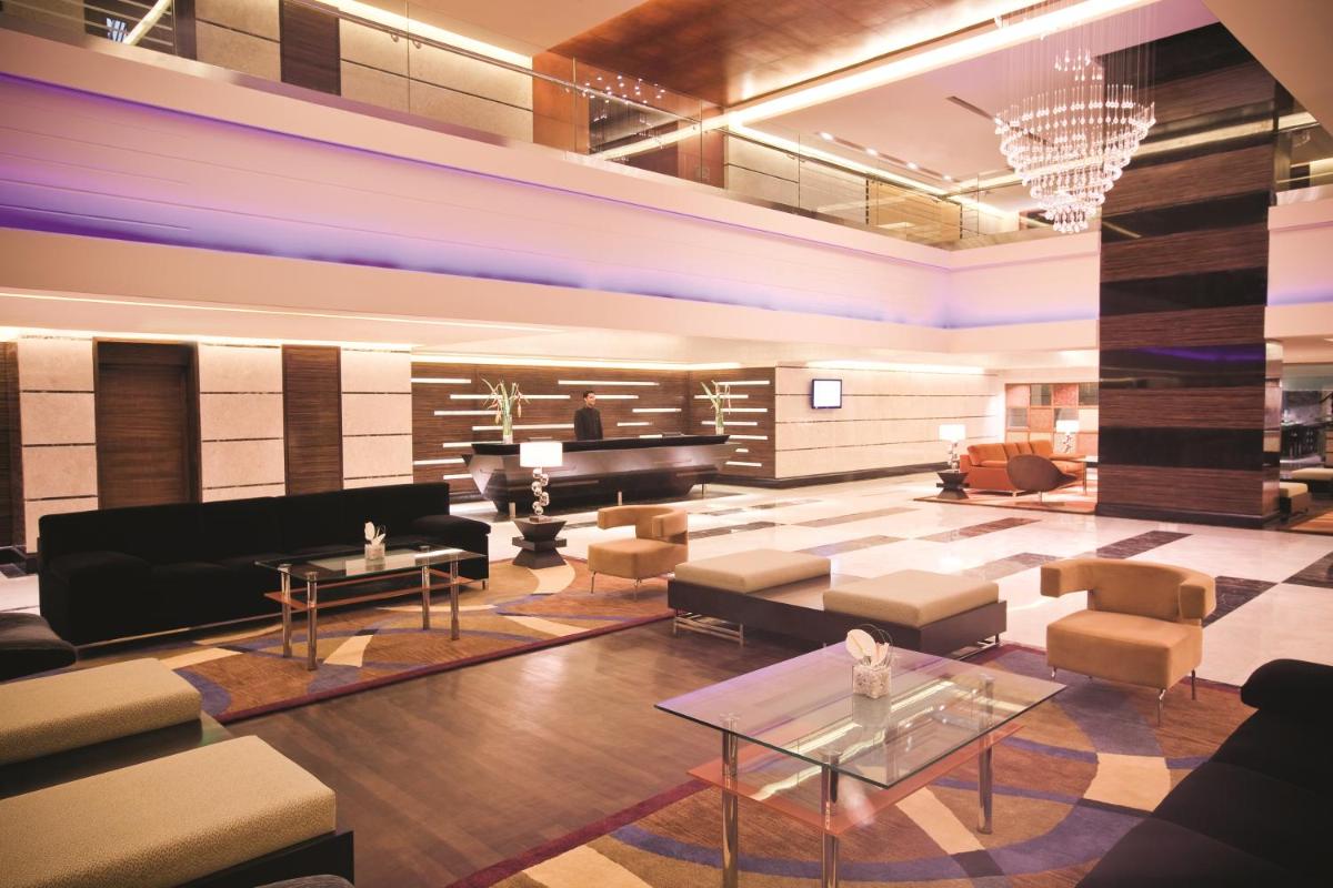 a living room with a piano and a couch and tables at Gokulam Grand Hotel & Spa Bangalore in Bengaluru a living room with a piano and a couch and tables at Gokulam Grand Hotel & Spa Bangalore in Bengaluru