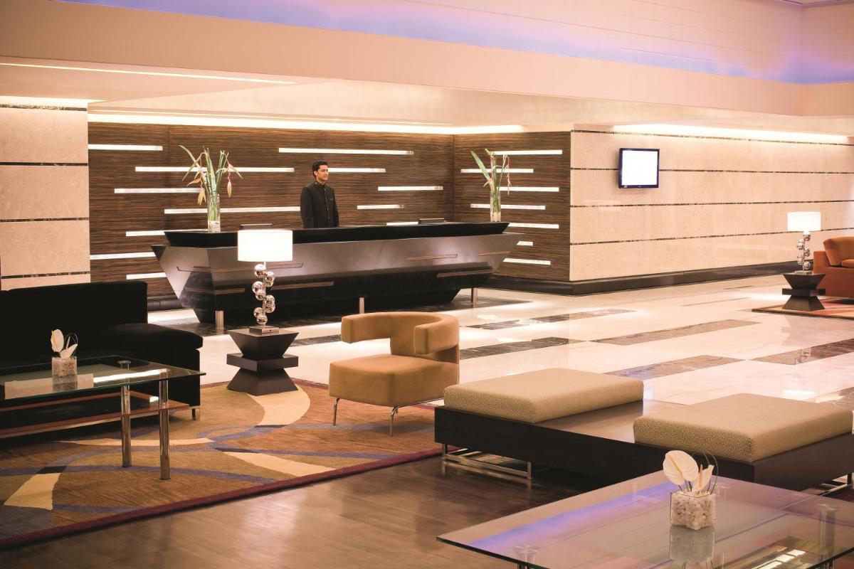 a man standing in front of a piano in a lobby at Gokulam Grand Hotel & Spa Bangalore in Bengaluru a man standing in front of a piano in a lobby at Gokulam Grand Hotel & Spa Bangalore in Bengaluru