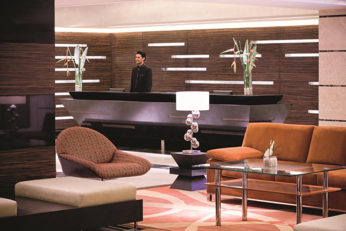 a man standing in front of a piano in a living room at Gokulam Grand Hotel & Spa Bangalore in Bengaluru a man standing in front of a piano in a living room at Gokulam Grand Hotel & Spa Bangalore in Bengaluru