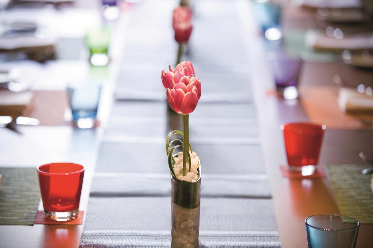 a vase with a red flower in it on a table at Gokulam Grand Hotel & Spa Bangalore in Bengaluru a vase with a red flower in it on a table at Gokulam Grand Hotel & Spa Bangalore in Bengaluru