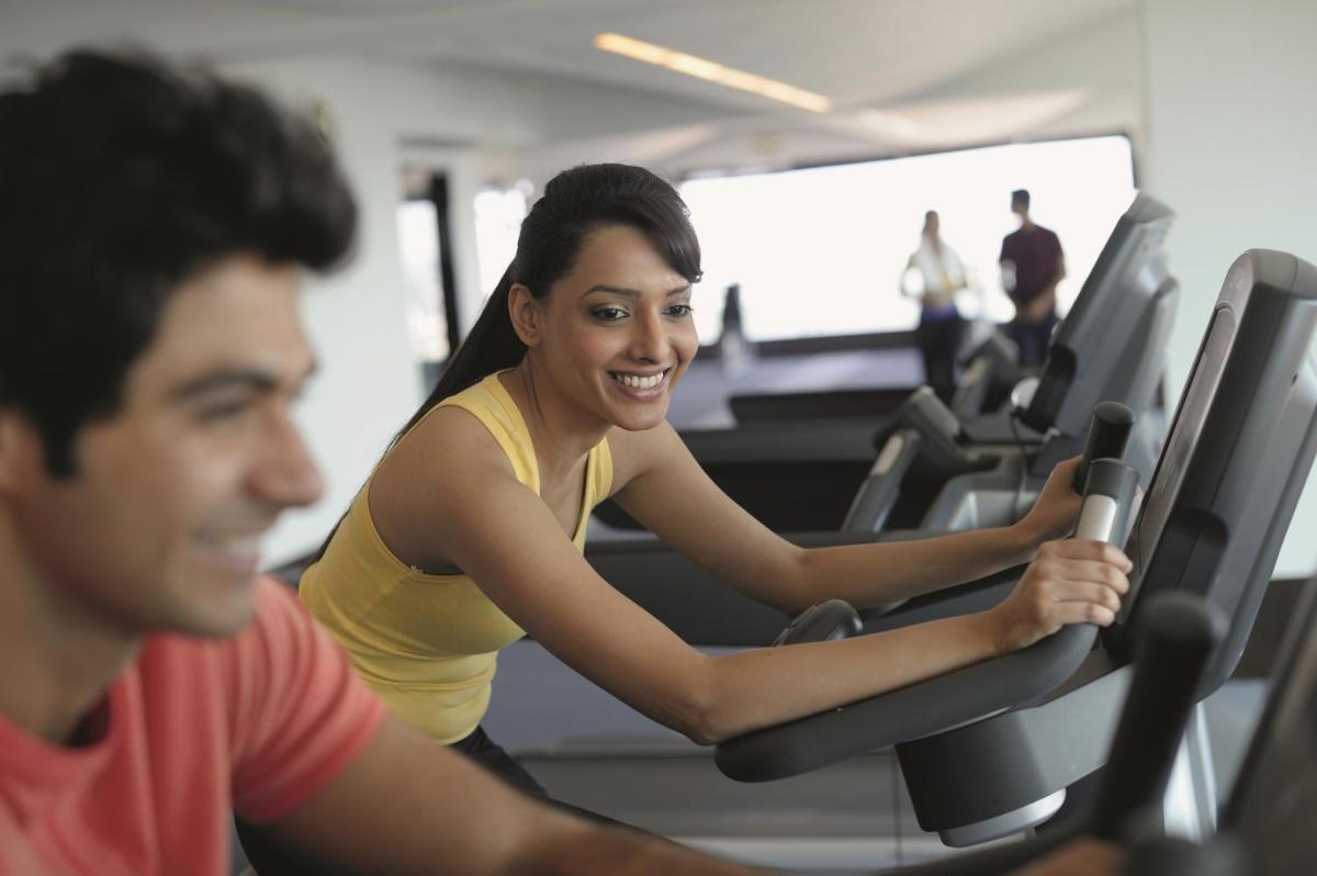 a man and woman riding on a treadmill in a gym at Gokulam Grand Hotel & Spa Bangalore in Bengaluru a man and woman riding on a treadmill in a gym at Gokulam Grand Hotel & Spa Bangalore in Bengaluru