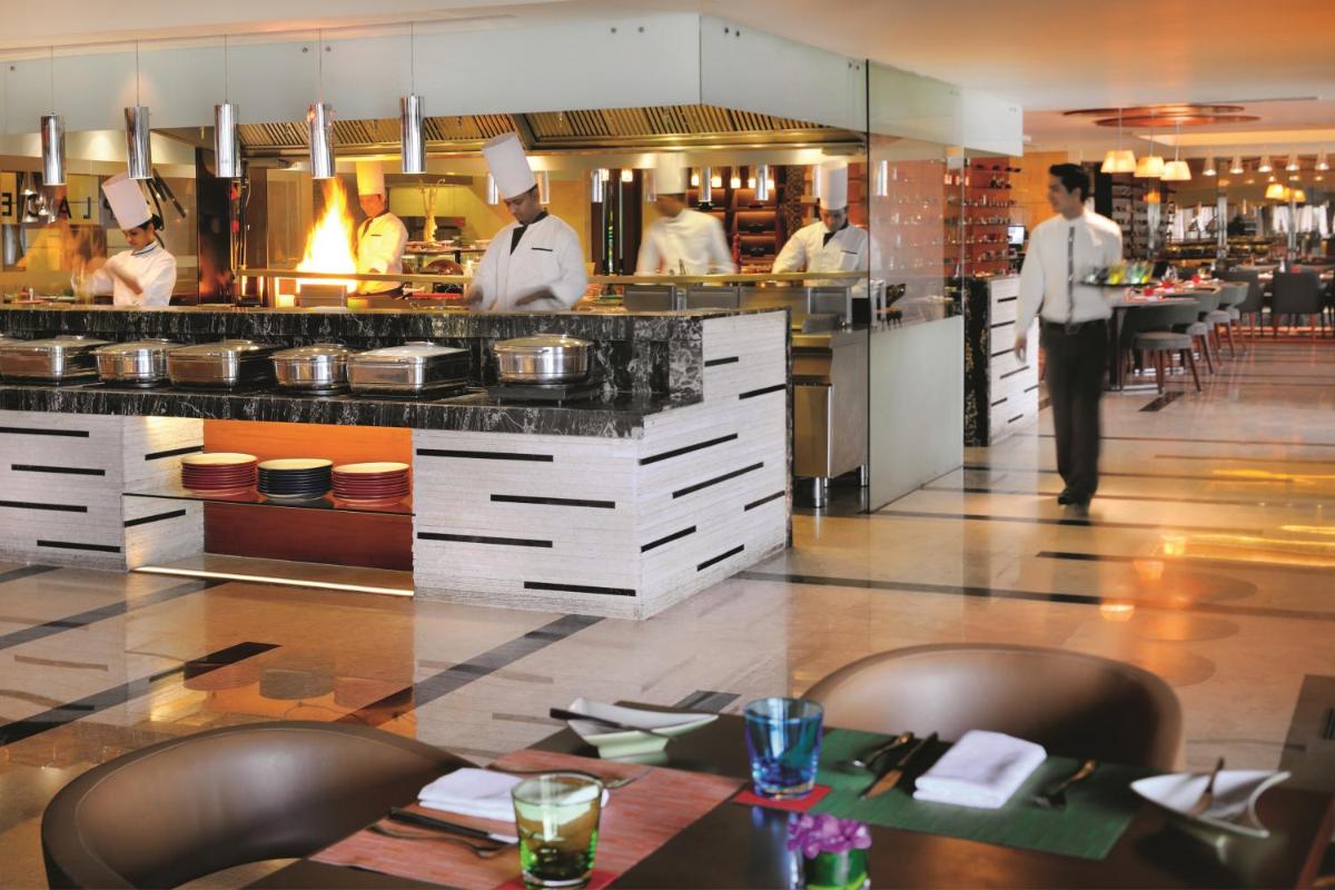 a restaurant with chefs working in a kitchen at Gokulam Grand Hotel & Spa Bangalore in Bengaluru a restaurant with chefs working in a kitchen at Gokulam Grand Hotel & Spa Bangalore in Bengaluru