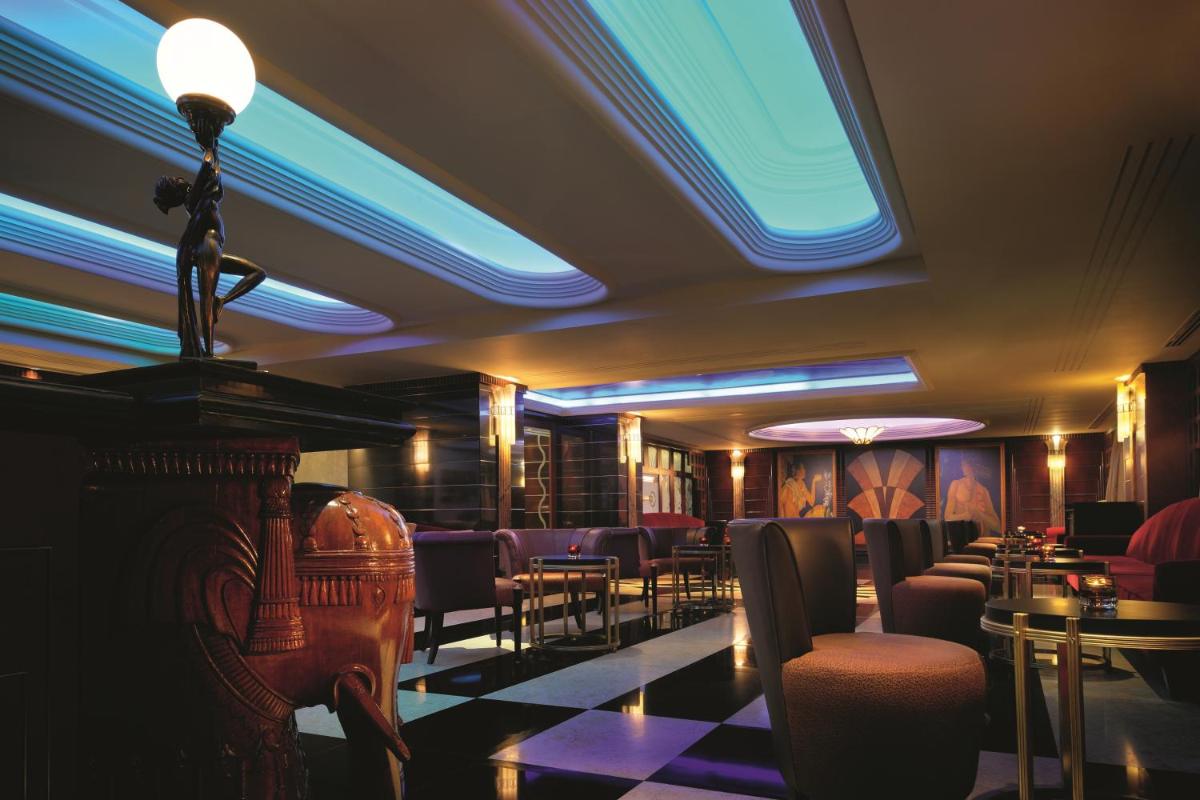 a room with a bar with chairs and tables at Gokulam Grand Hotel & Spa Bangalore in Bengaluru a room with a bar with chairs and tables at Gokulam Grand Hotel & Spa Bangalore in Bengaluru