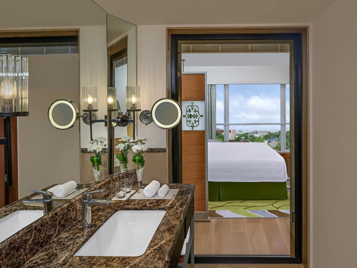 a bathroom with two sinks and a room with a bed at ITC Kakatiya, a Luxury Collection Hotel, Hyderabad in Hyderabad