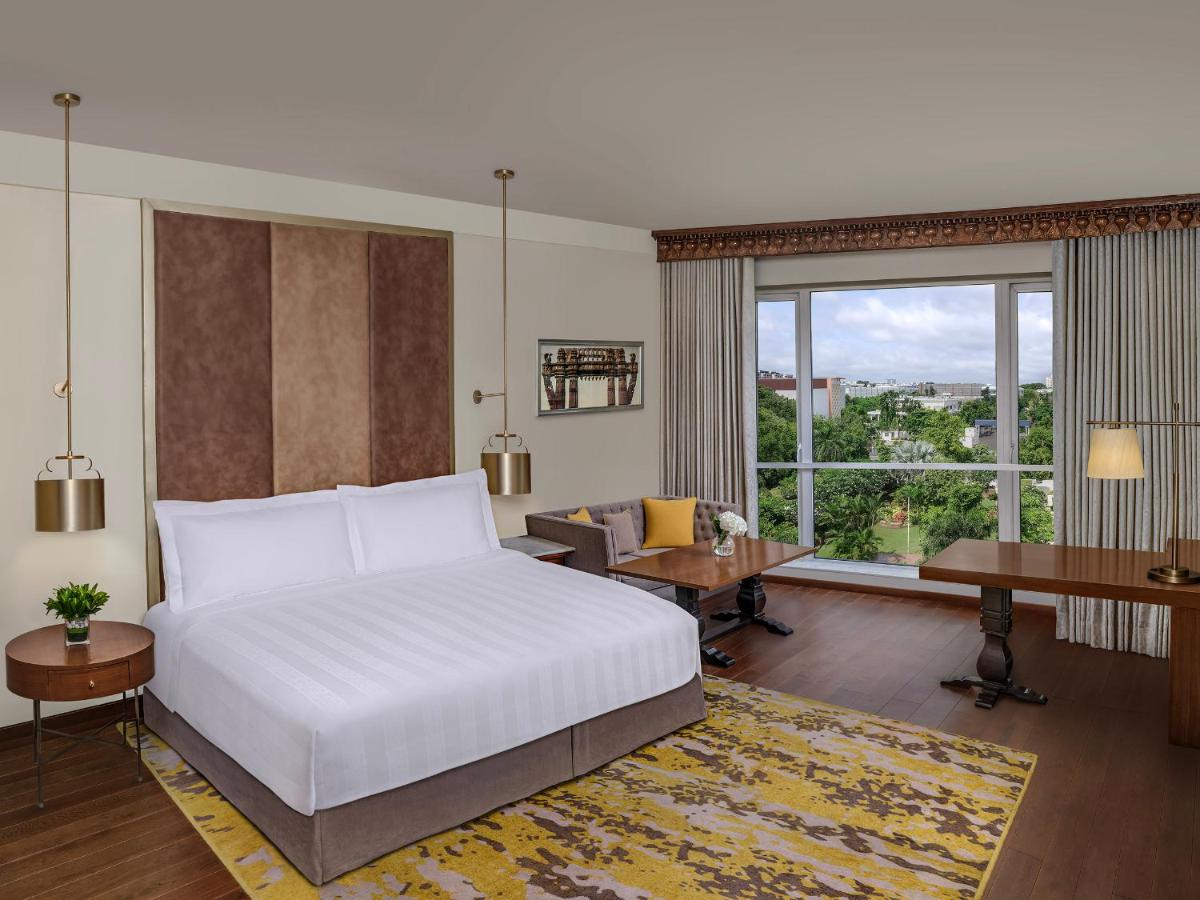 a bedroom with a white bed and a desk and a window at ITC Kakatiya, a Luxury Collection Hotel, Hyderabad in Hyderabad