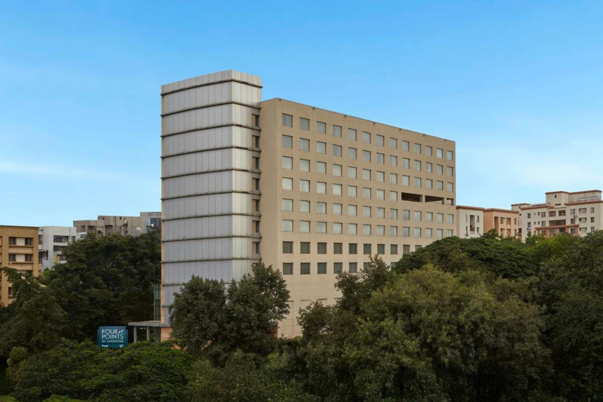 a tall white building in the middle of a city at Four Points by Sheraton Hotel and Serviced Apartments Pune in Pune