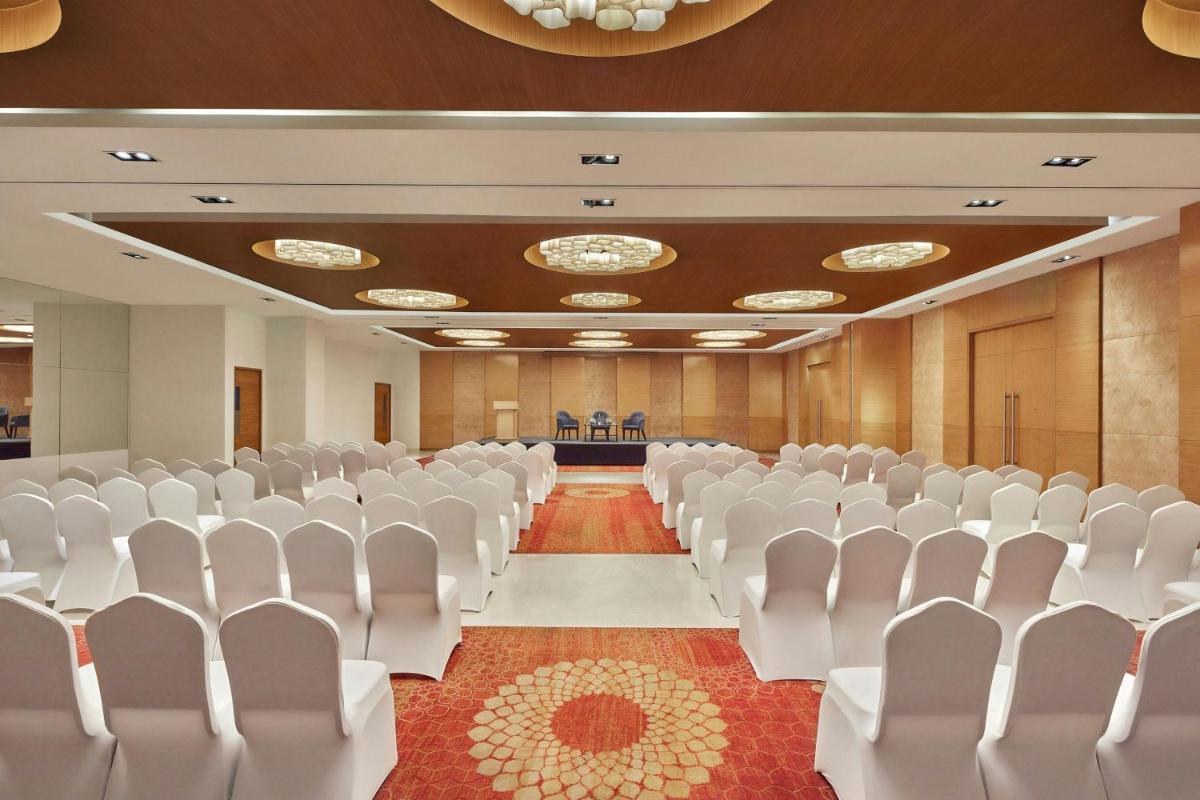 an empty conference room with white chairs and a stage at Four Points by Sheraton Hotel and Serviced Apartments Pune in Pune
