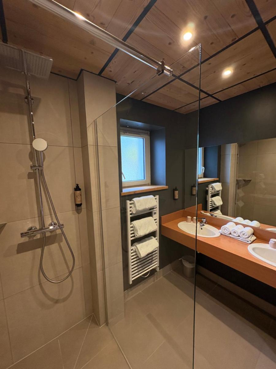 une salle de bains avec deux lavabos et une douche dans l'établissement Les Reflets du Lac, à Gérardmer 52 autres photos