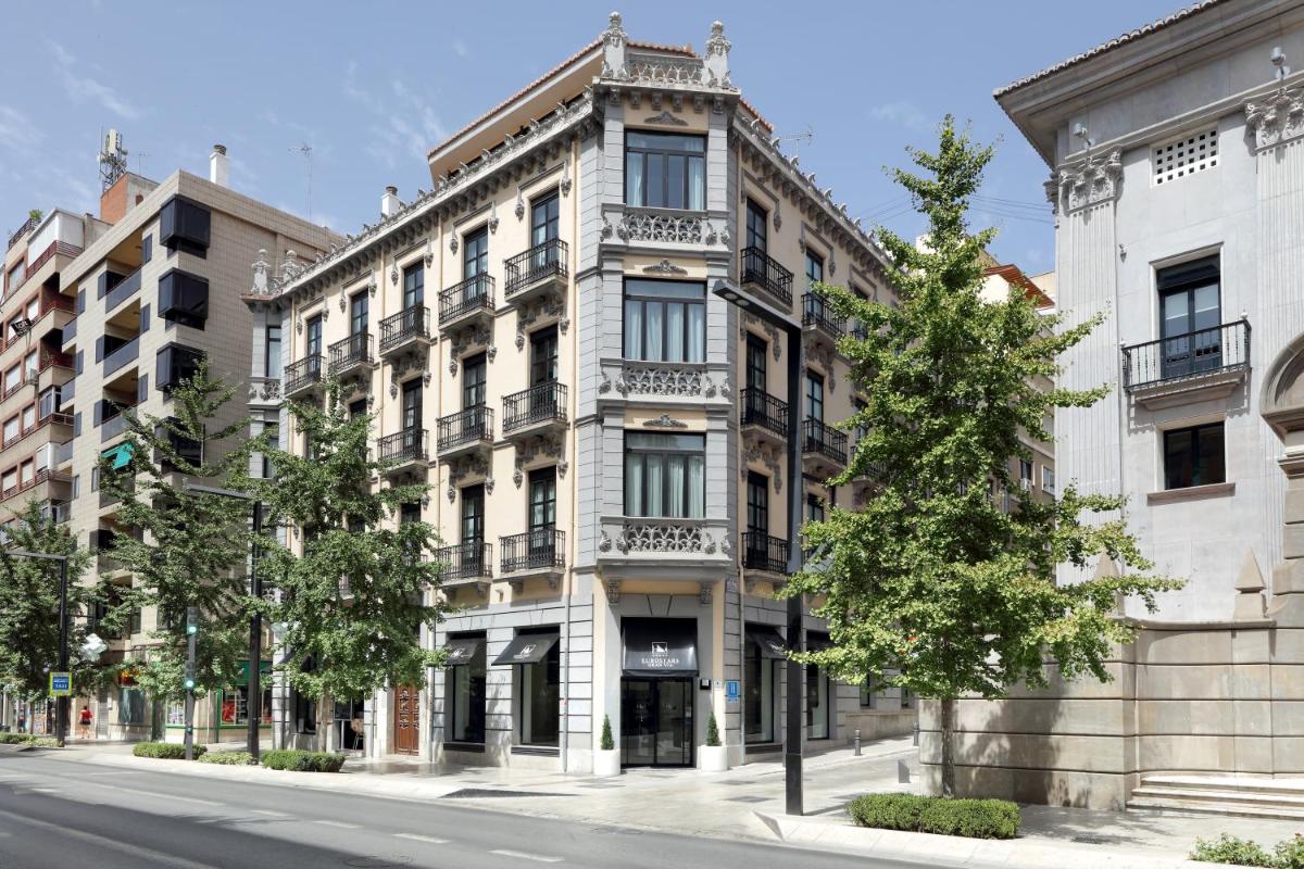 Un edificio de apartamentos en una calle con árboles al frente. en Eurostars Gran Via, en Granada