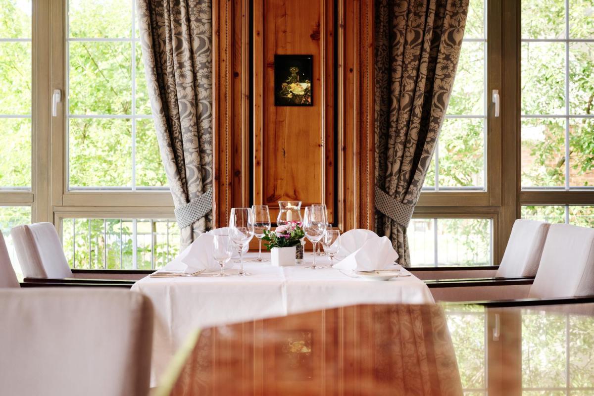 ein Tisch mit Weingläsern in einem Zimmer mit Fenstern in der Unterkunft Hotel Dollenberg in Bad Peterstal-Griesbach