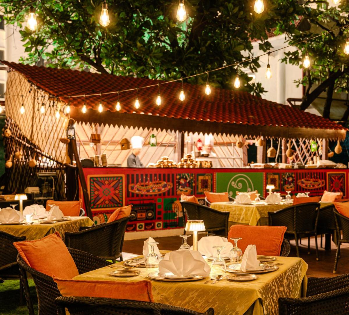 a restaurant with tables and chairs and lights at Novotel Mumbai Juhu Beach in Mumbai
