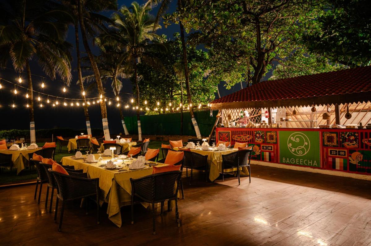 a restaurant with tables and chairs and lights at Novotel Mumbai Juhu Beach in Mumbai