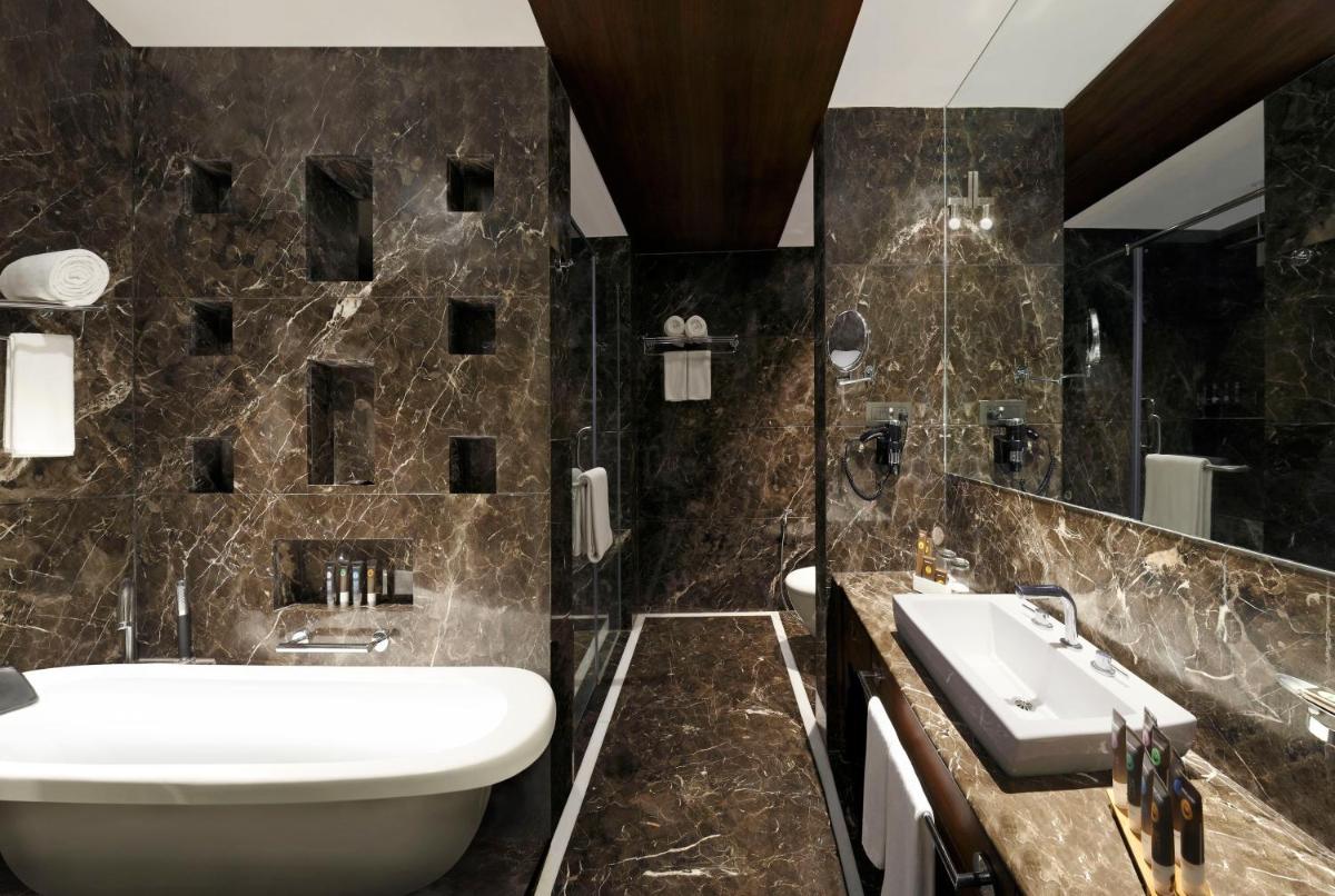 a bathroom with a sink and a toilet and a tub at Novotel Mumbai Juhu Beach in Mumbai