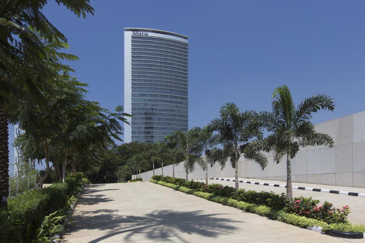 a road in front of a tall building with palm trees at The Westin Mumbai Garden City in Mumbai
