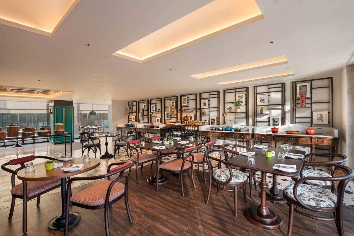 a restaurant with tables and chairs in a room at Hyatt Centric Rajpur Road Dehradun in Dehradun