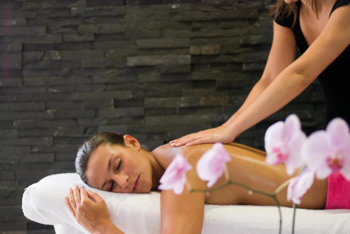une femme recevant un massage dans un lit dans l'établissement Hôtel Le Nouveau Monde, à Saint-Malo