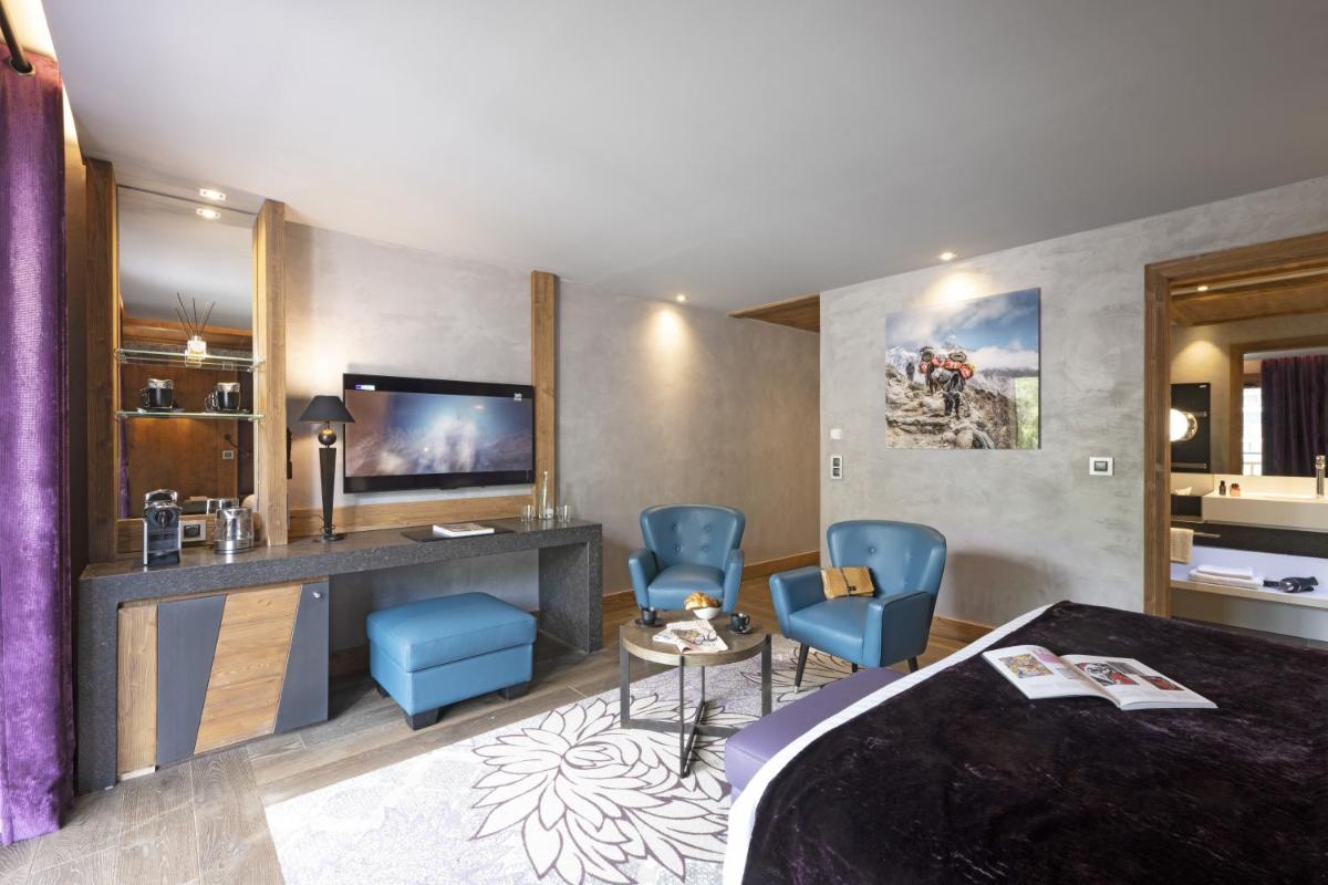 une chambre d'hôtel avec un lit et deux chaises bleues dans l'établissement MGM Hôtels & Résidences - Hôtel Les Suites d'Alexane, à Samoëns