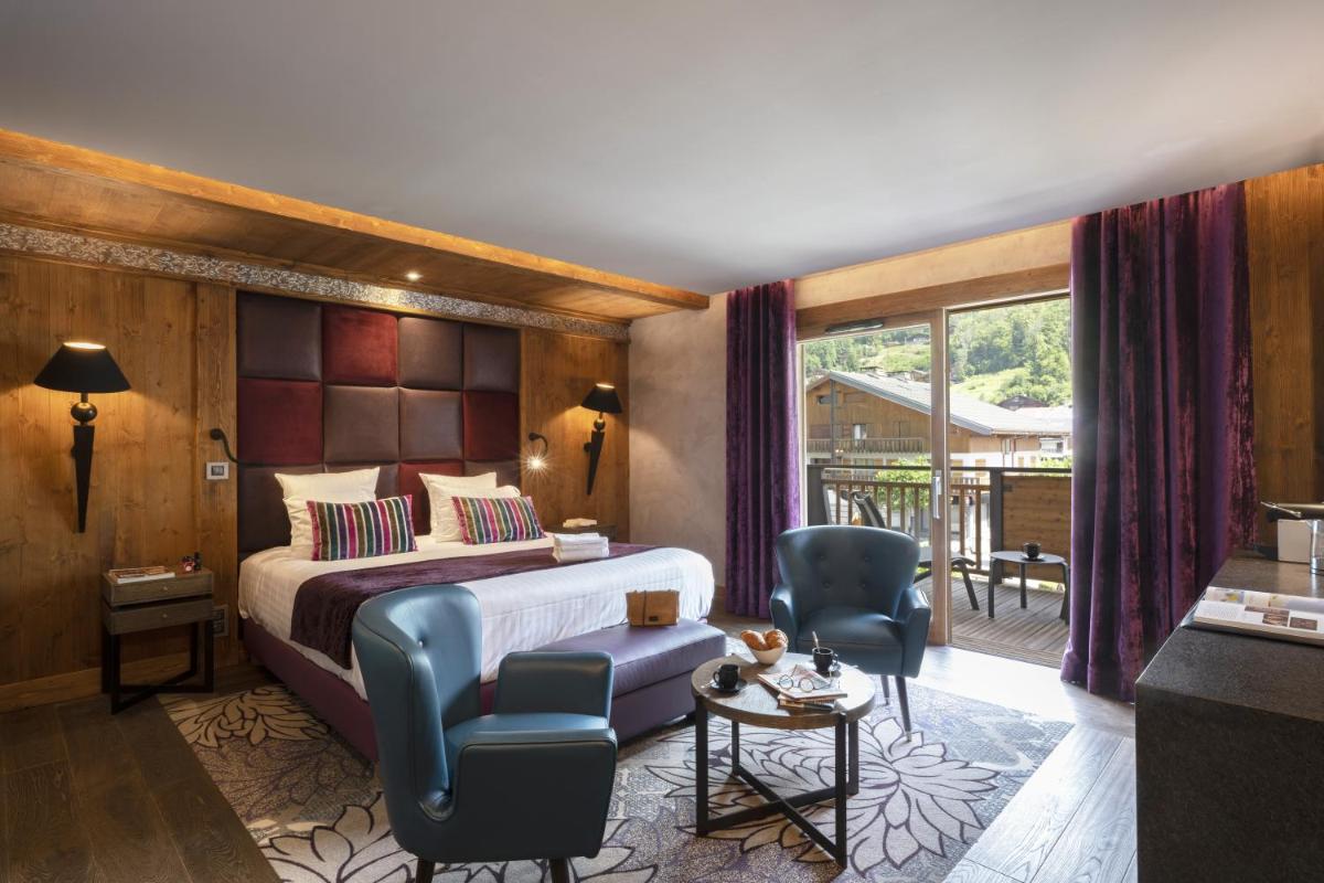 une chambre d'hôtel avec un lit et deux chaises dans l'établissement MGM Hôtels & Résidences - Hôtel Les Suites d'Alexane, à Samoëns