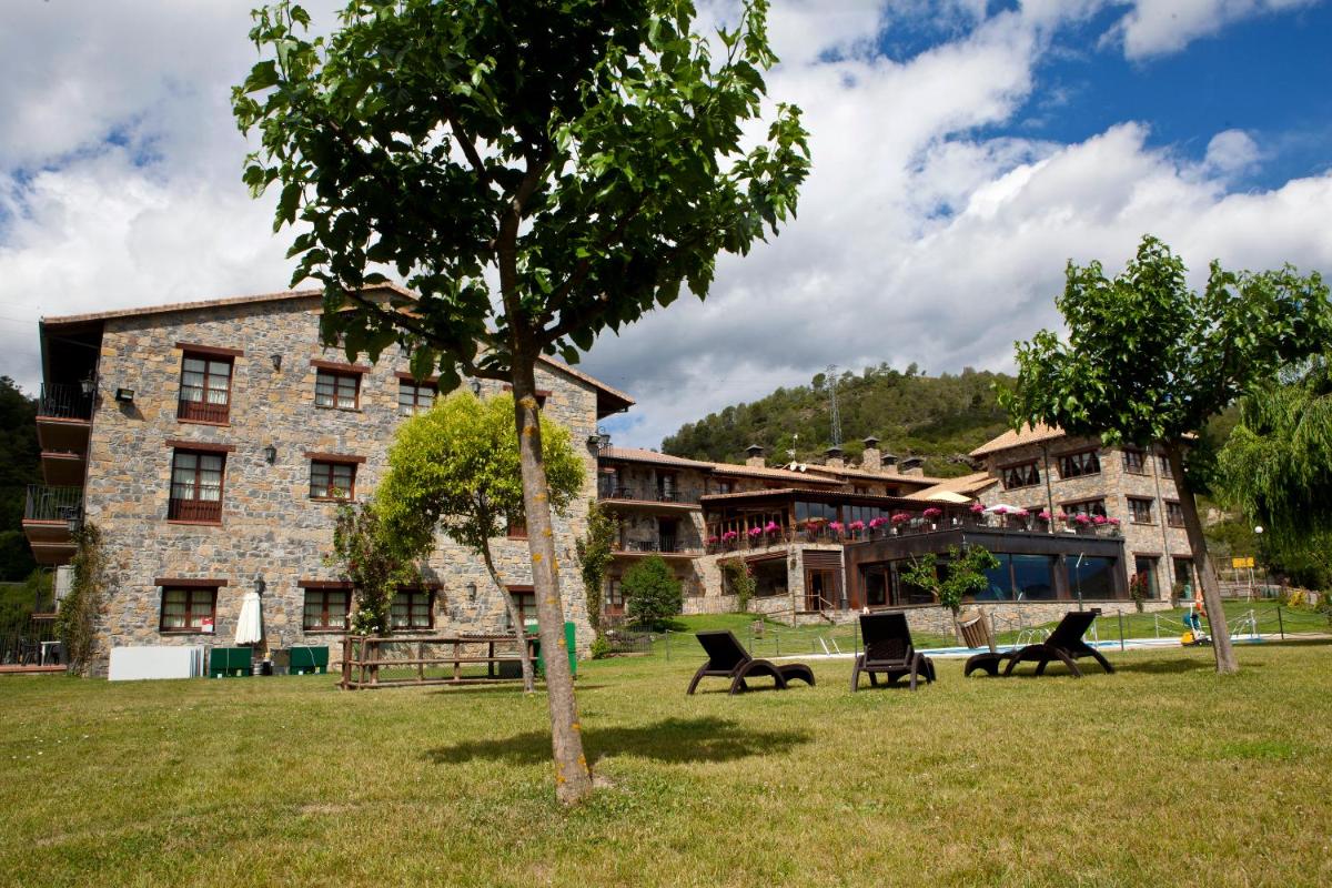 un edificio con sillas y un árbol delante de él en Hotel & SPA Peña Montañesa, en Aínsa