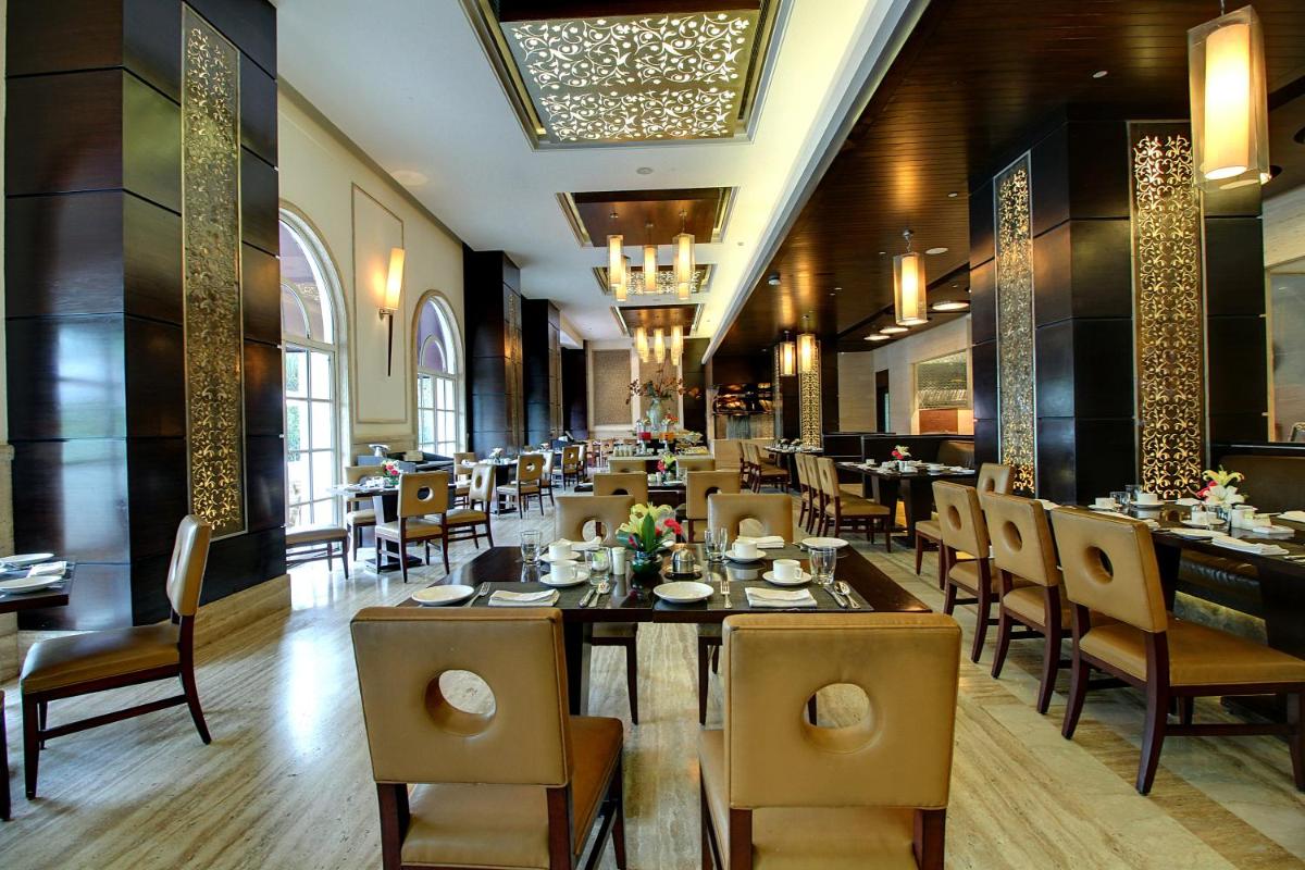 a dining room with tables and chairs in a restaurant at The Pllazio Hotel in Gurgaon