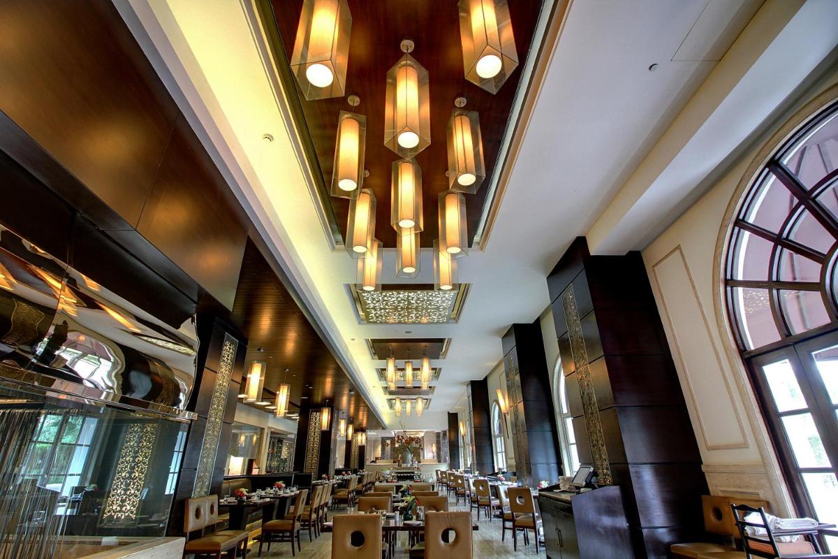 a restaurant with tables and chairs and chandeliers at The Pllazio Hotel in Gurgaon