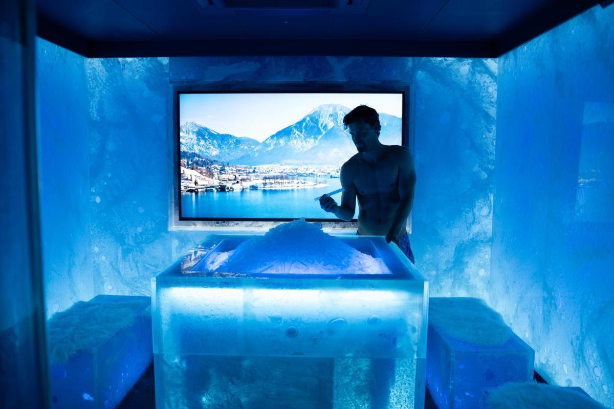 ein Mann in einem blauen Raum mit einem Fernseher in einer Eishöhle in der Unterkunft Parkhotel Egerner Höfe in Rottach-Egern