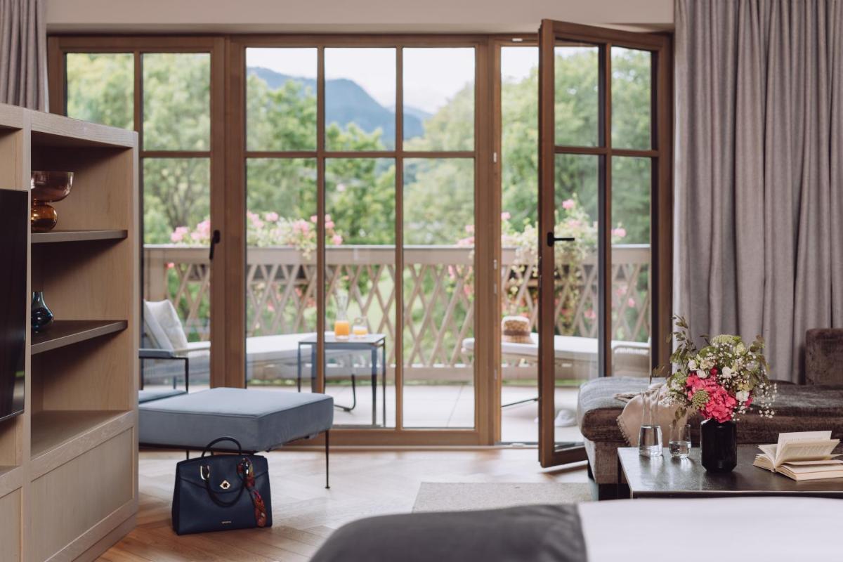 ein Wohnzimmer mit einer großen Glasschiebetür in der Unterkunft Parkhotel Egerner Höfe in Rottach-Egern