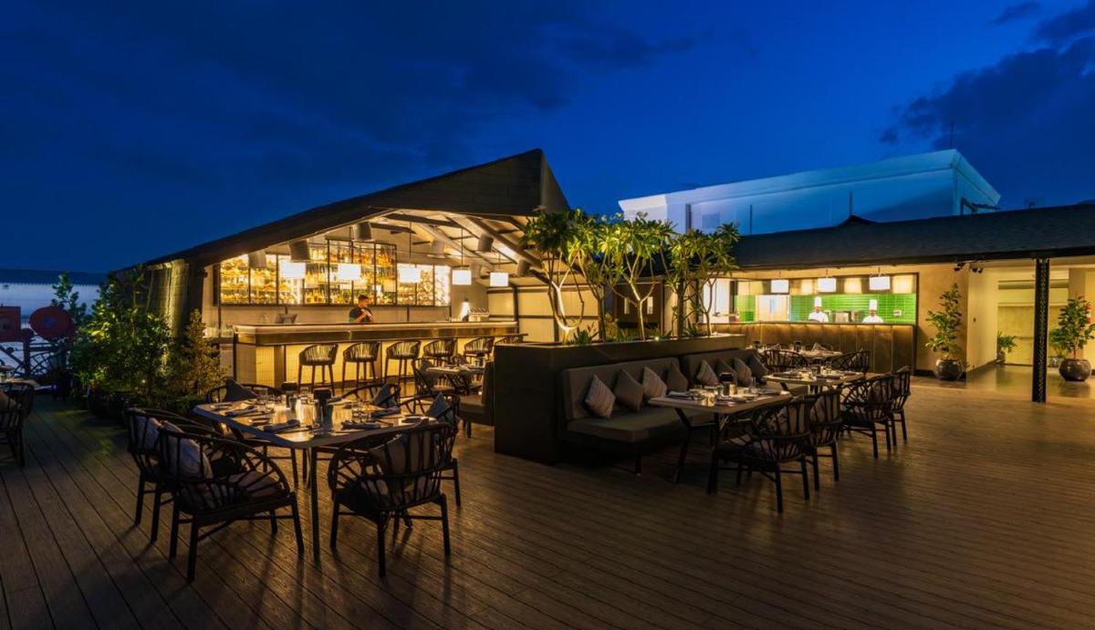 a restaurant with tables and chairs on a deck at night at The Residency Towers Puducherry in Puducherry