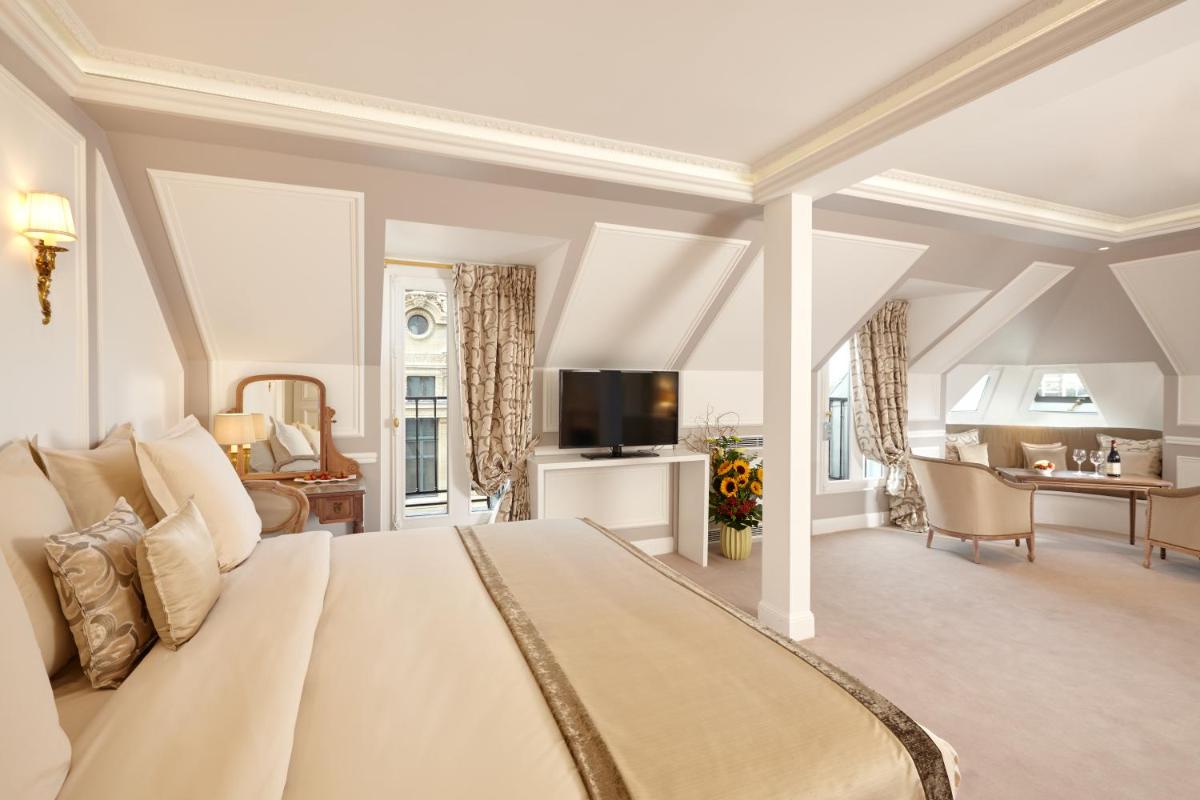une chambre avec un grand lit et un salon dans l'établissement Hôtel Regina Louvre, à Paris