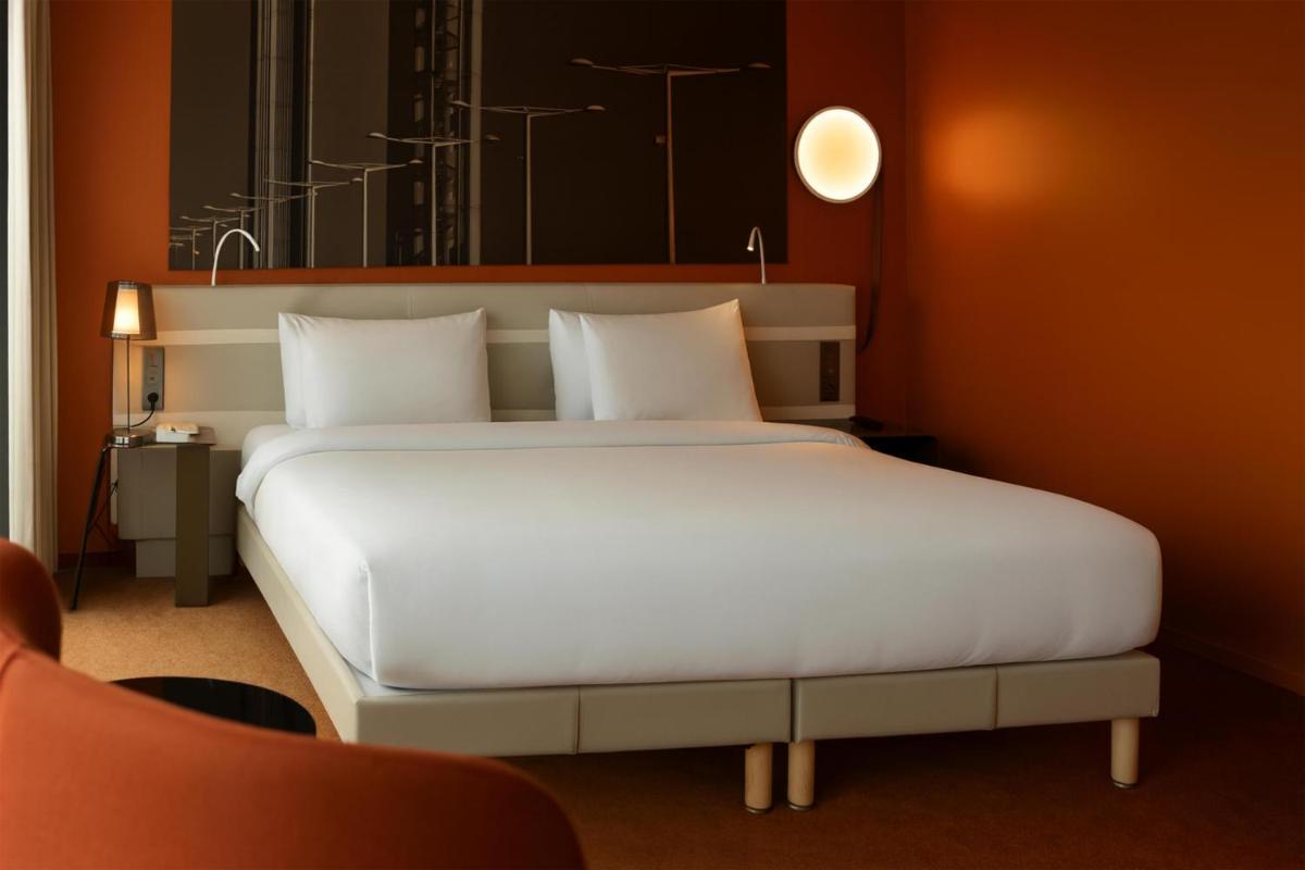 un grand lit blanc dans une chambre aux murs rouges dans l'établissement Radisson Blu Hotel Bordeaux, à Bordeaux 91 autres photos