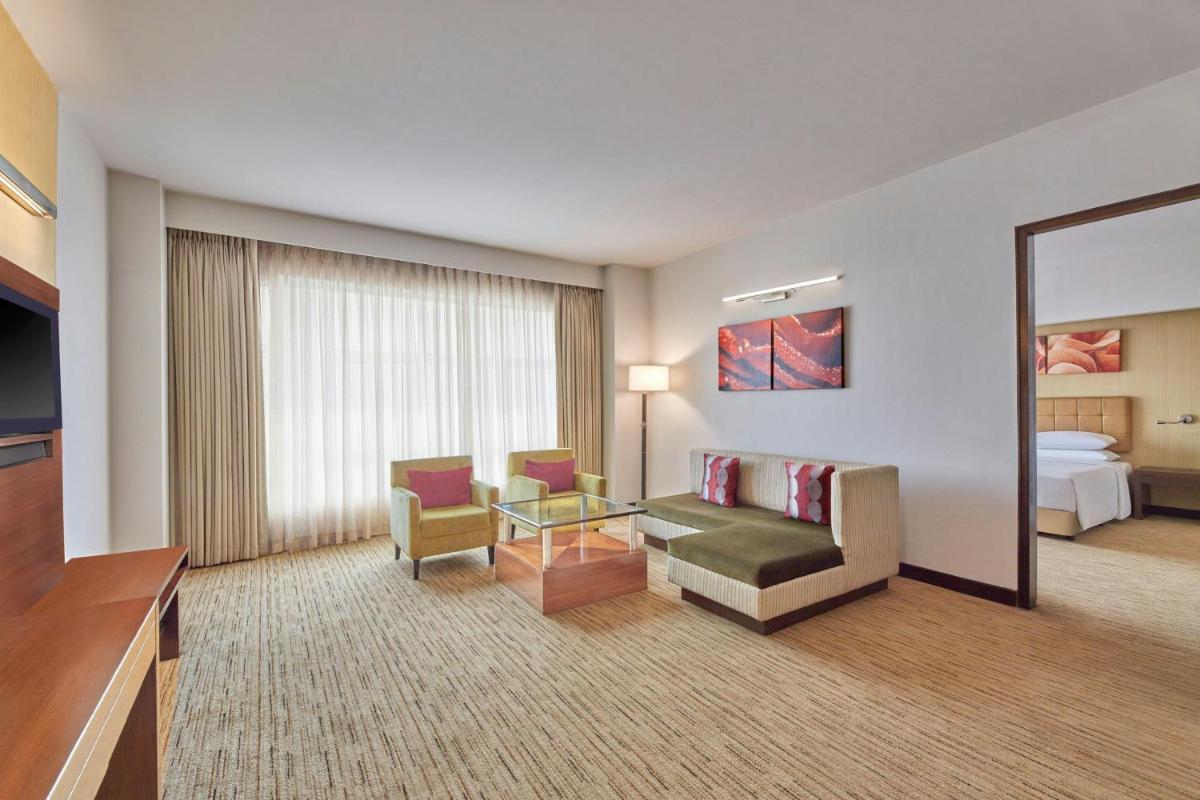 a hotel room with a couch and chairs and a bed at Four Points by Sheraton Hotel and Serviced Apartments Pune in Pune