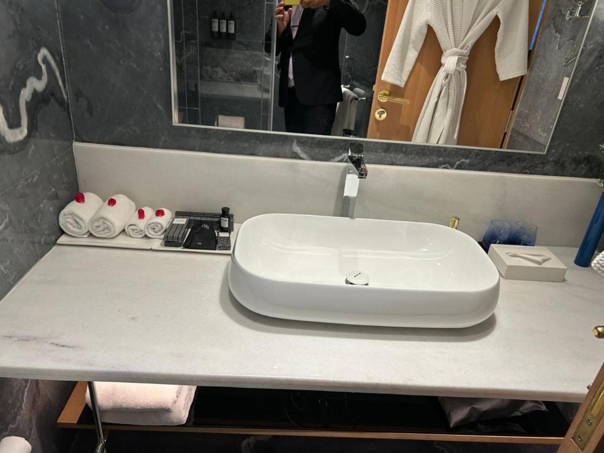 a white sink in a bathroom with a person taking a picture at The Park New Delhi in New Delhi