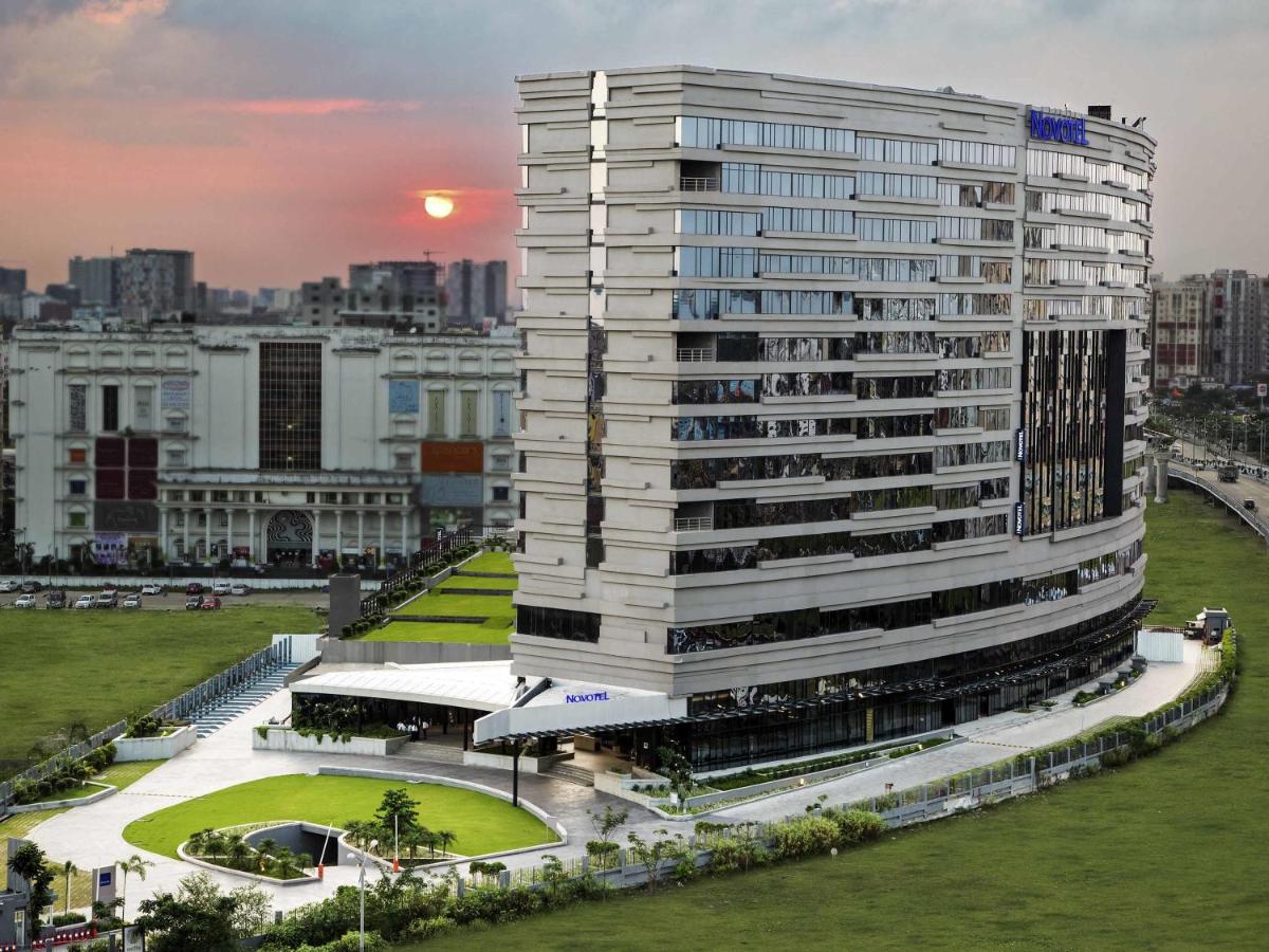 Un edificio alto y blanco con un parque enfrente. en Novotel Kolkata Hotel and Residences, en Calcuta Un edificio alto y blanco con un parque enfrente. en Novotel Kolkata Hotel and Residences, en Calcuta