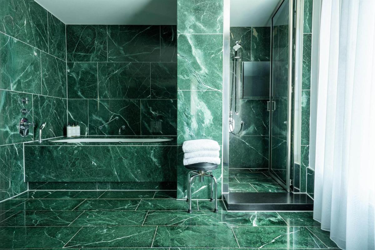 ein grünes Badezimmer mit Badewanne und Stuhl in der Unterkunft Grand Hyatt Berlin in Berlin