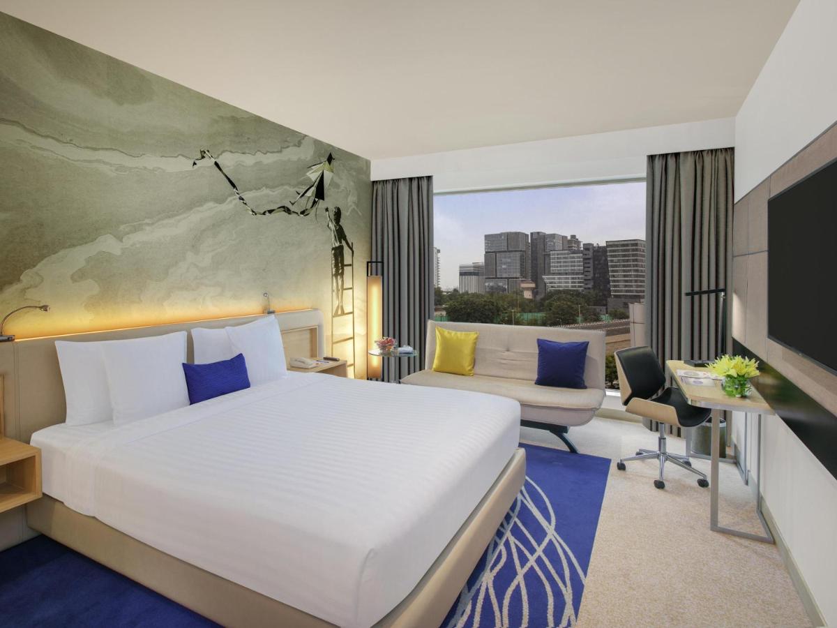 a hotel room with a bed and a large window at Novotel Ahmedabad in Ahmedabad