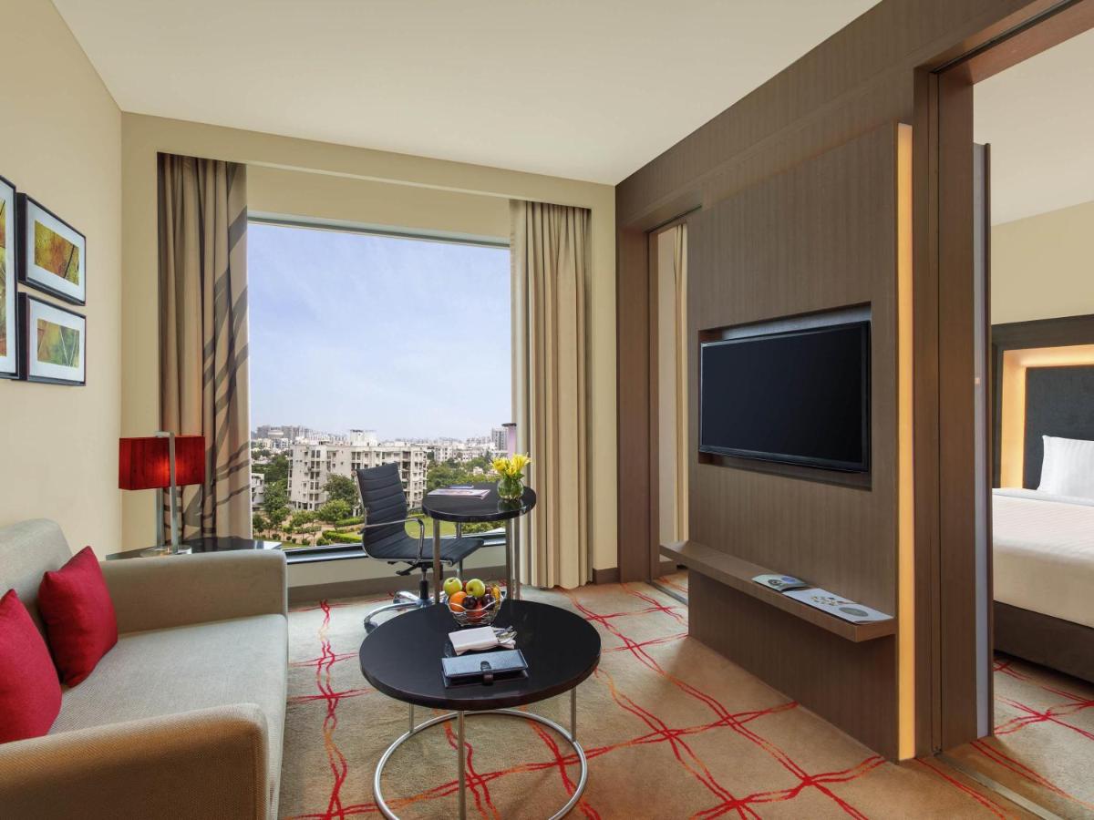 a living room with a couch and a tv at Novotel Ahmedabad in Ahmedabad