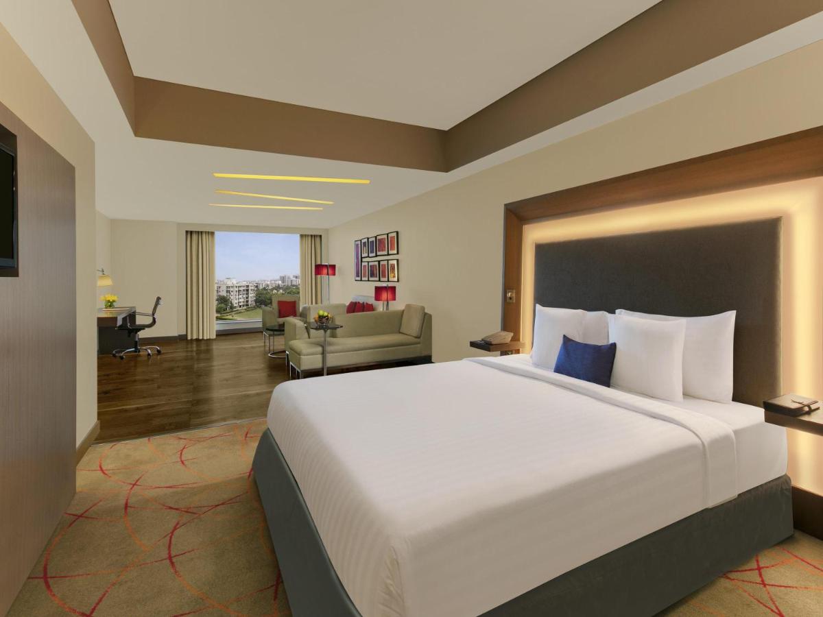 a hotel room with a large bed and a living room at Novotel Ahmedabad in Ahmedabad