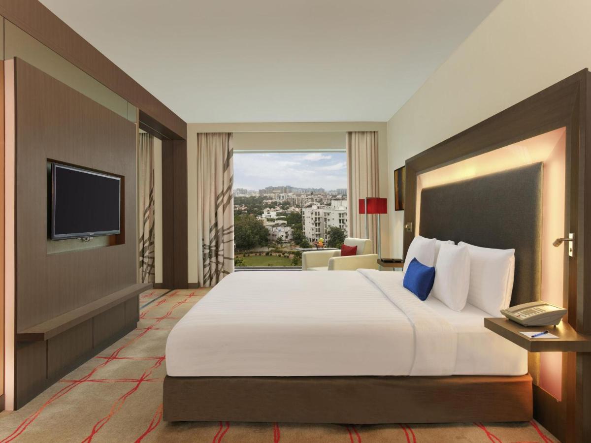 a hotel room with a large bed and a television at Novotel Ahmedabad in Ahmedabad