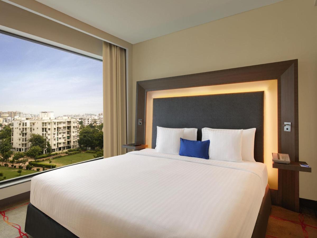 a bedroom with a large bed with a large window at Novotel Ahmedabad in Ahmedabad