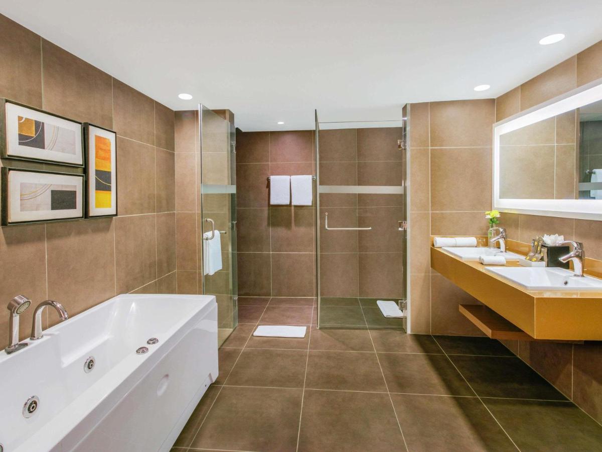 a bathroom with a tub and a sink and a shower at Novotel Ahmedabad in Ahmedabad