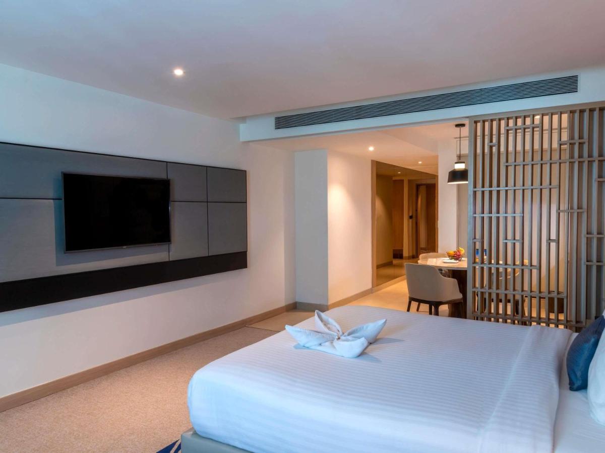 a bedroom with a white bed and a television at Novotel Ahmedabad in Ahmedabad