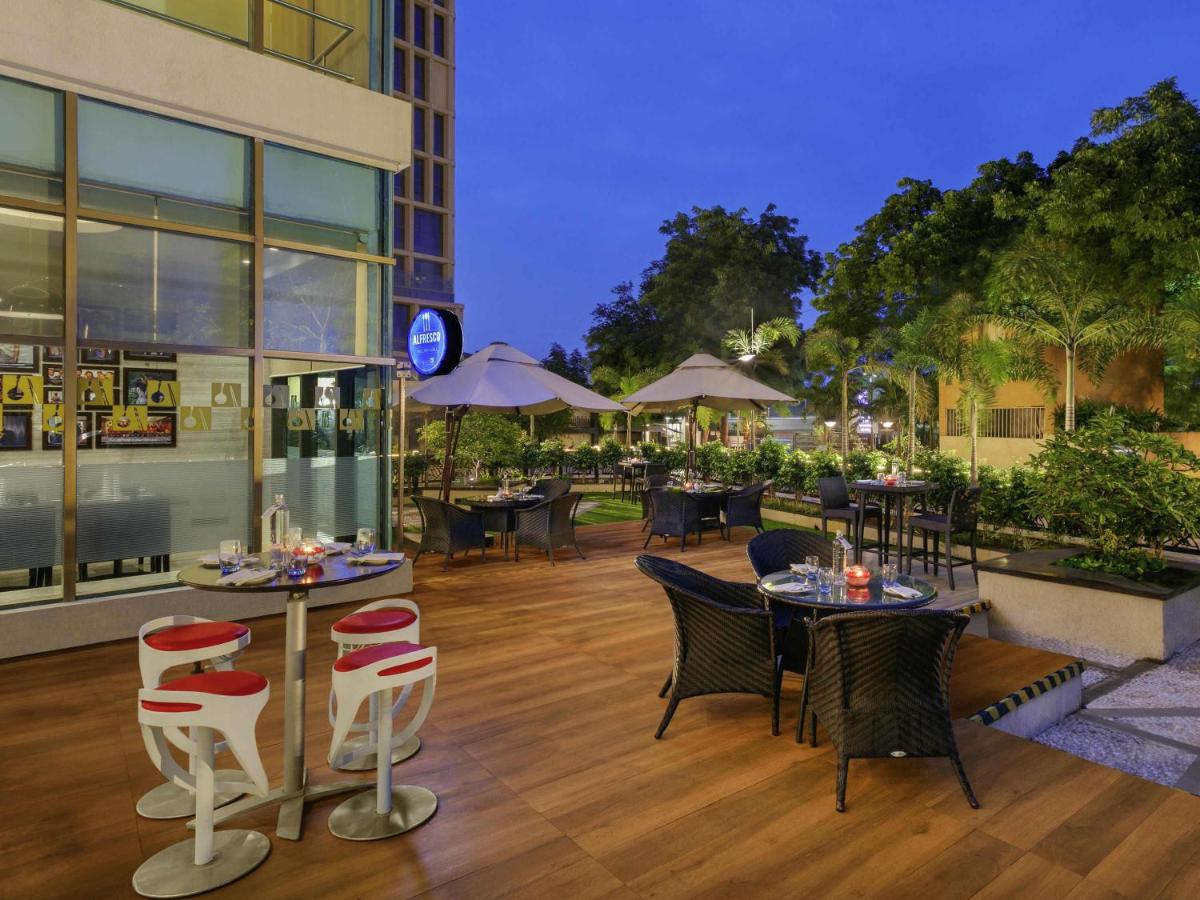 a restaurant with tables and chairs on a wooden floor at Novotel Ahmedabad in Ahmedabad