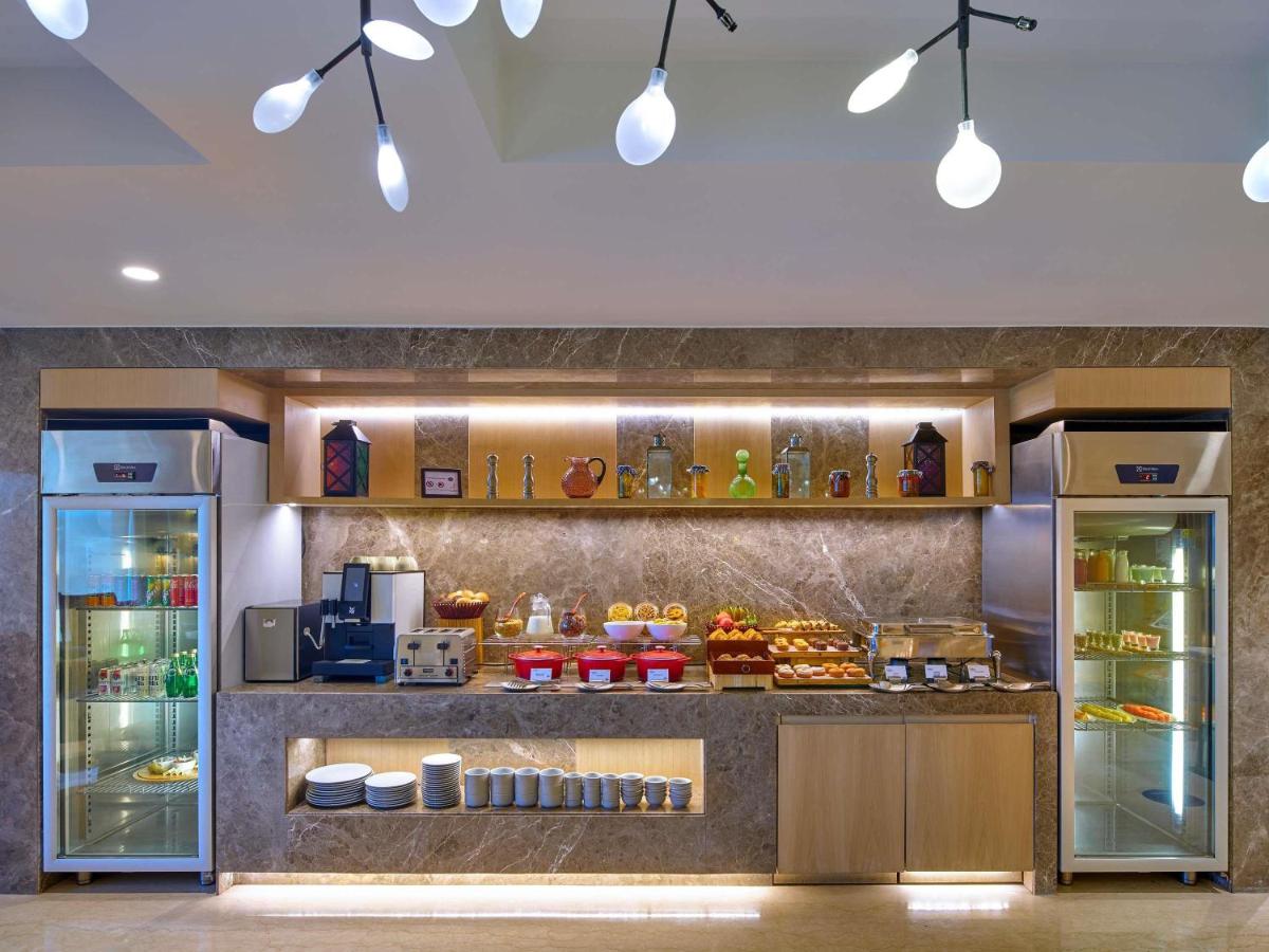 a bakery with a counter with food in it at Novotel Ahmedabad in Ahmedabad