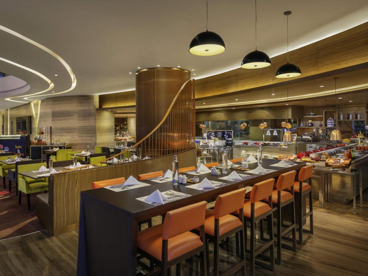 a dining room with a long table and chairs at Novotel Ahmedabad in Ahmedabad