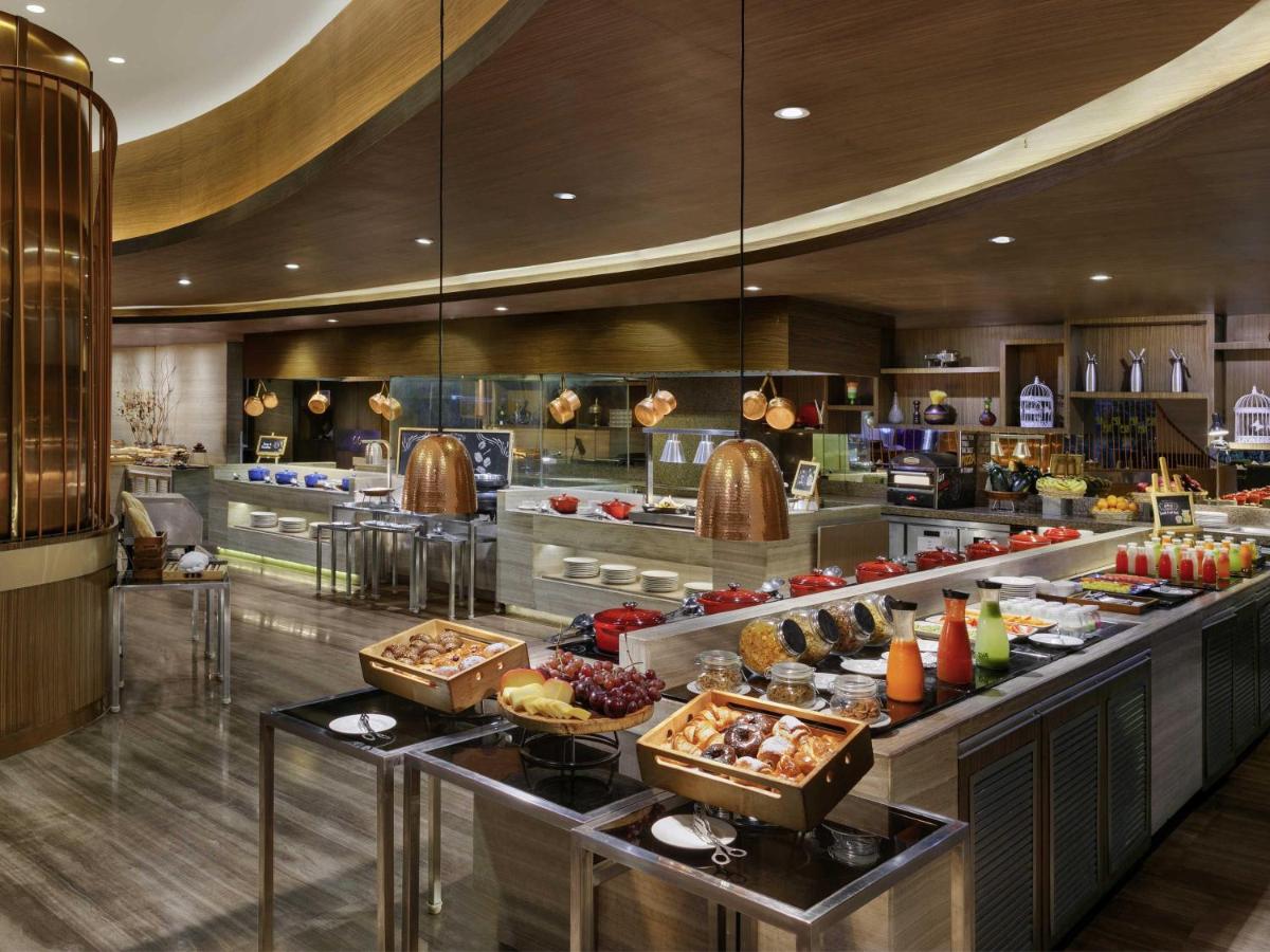 a buffet in a restaurant with food on display at Novotel Ahmedabad in Ahmedabad