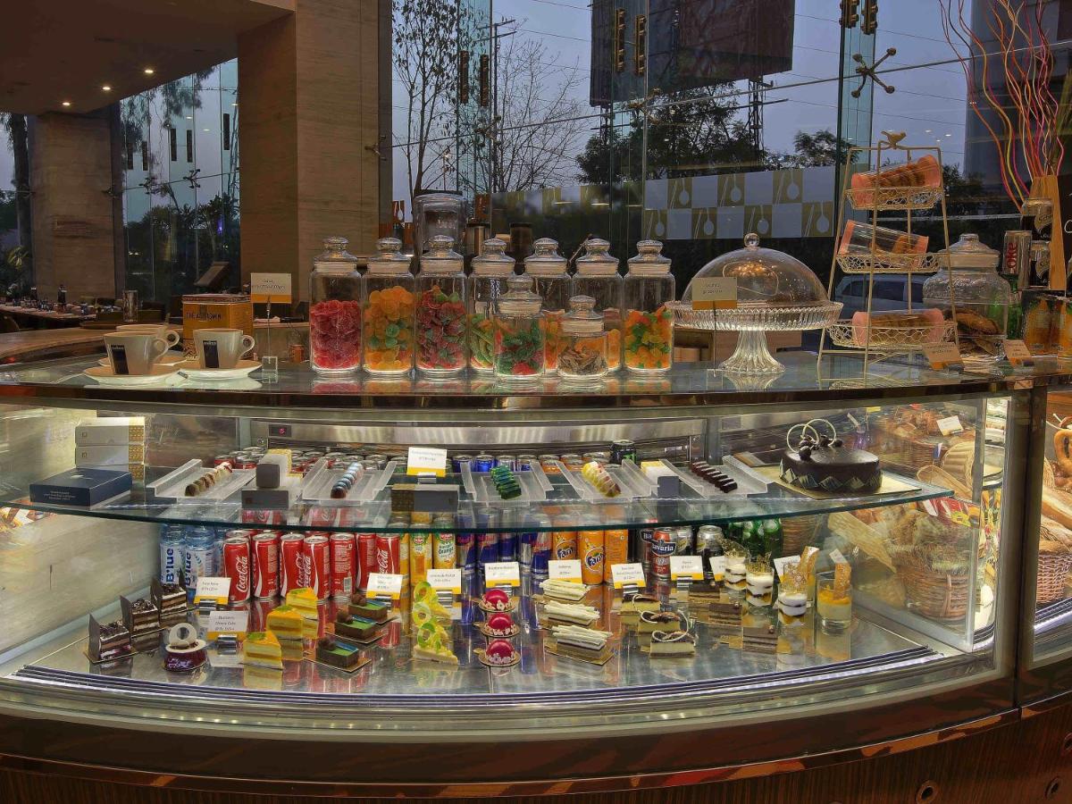 a display case filled with different types of food at Novotel Ahmedabad in Ahmedabad