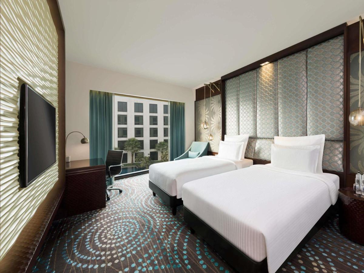 a hotel room with two beds and a flat screen tv at Pullman New Delhi Aerocity in New Delhi