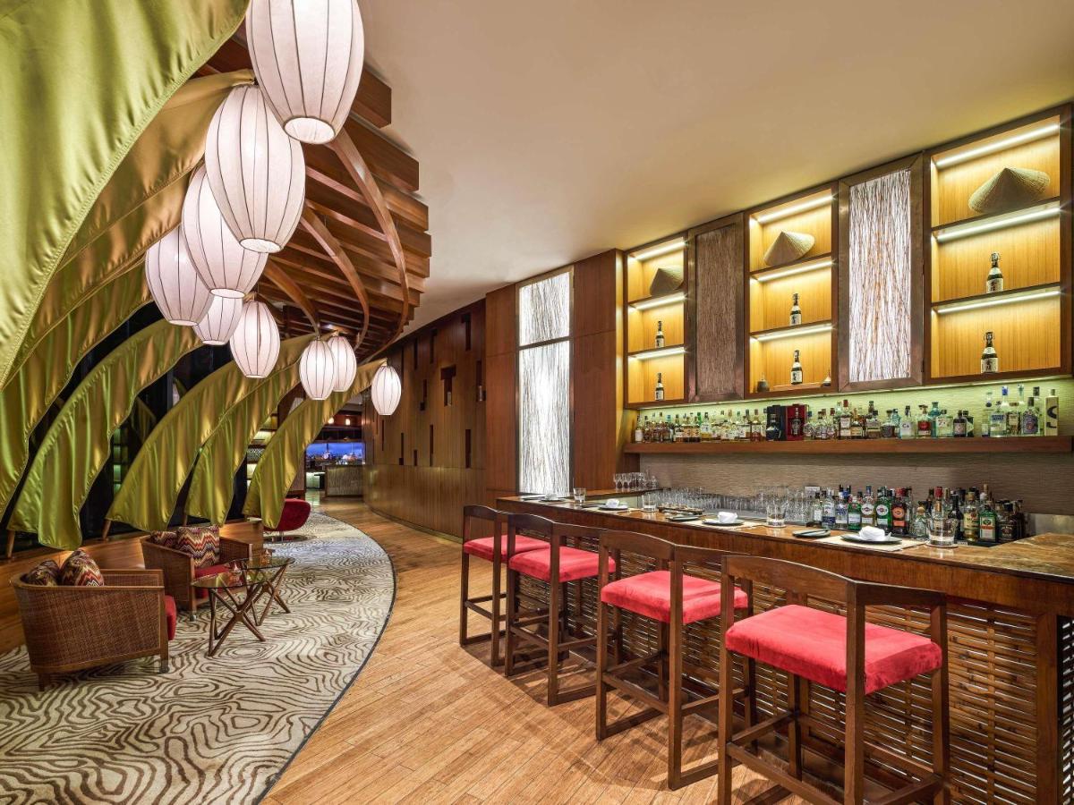 a restaurant with a bar with red stools at Pullman New Delhi Aerocity in New Delhi