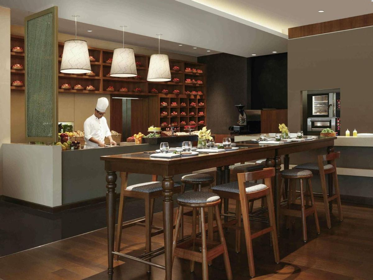 a kitchen with a bar with a chef in the kitchen at Pullman New Delhi Aerocity in New Delhi